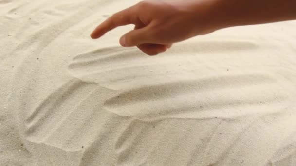 Χέρι σχεδιάζει την επιγραφή Μπαλί στην άμμο. Ηλιόλουστη ακτή της θάλασσας και του ωκεανού. Σύμβολο ξεκούρασης και διακοπών στο θέρετρο — Αρχείο Βίντεο