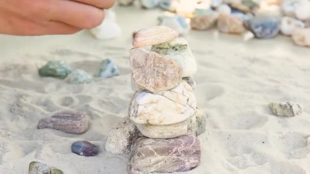 Man builds a pyramid of sea stones. heap of smooth pebbles. zen stones close-up. the concept of peace of mind and relaxation in the resort — Wideo stockowe