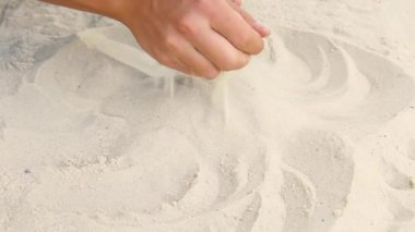 Beyaz deniz kumlarında erkeklerin elleri akın eder. Sahil oyunları. Deniz kıyısındaki kumu okşar. Tatil kavramı