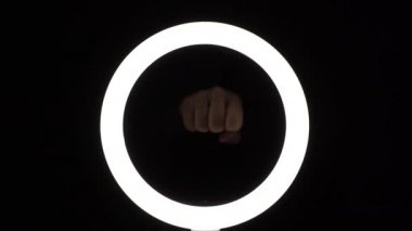 Kadın elleri çerçevede bir yumrukla vuruyor. Kadın hakları için savaş. Siyah arkaplanda yakın plan hareketler