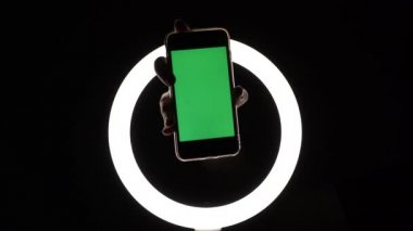 Kadın eli, telefonun siyah arka planda yakın çekimini gösteriyor. Reklam eklemek için yeşil ekran modeli. Parmakları ekranda gezdirir, tıklatmalar, kaydırmalar, yazılar