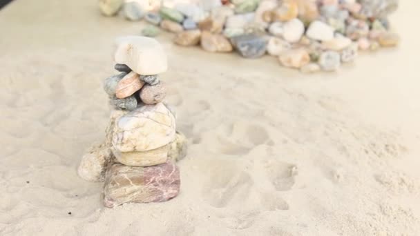 Colata di sabbia su una piramide di pietre marine. cumulo di ciottoli lisci. zen pietre primo piano. il concetto di tranquillità e relax nel resort — Video Stock