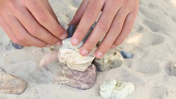 Man builds a pyramid of sea stones. heap of smooth pebbles. zen stones close-up. the concept of peace of mind and relaxation in the resort — Vídeo de Stock