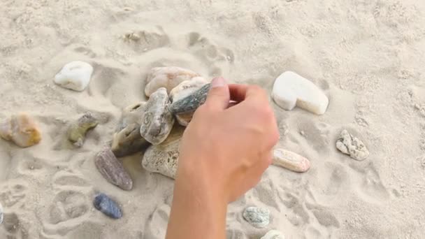 Man builds a pyramid of sea stones. heap of smooth pebbles. zen stones close-up. the concept of peace of mind and relaxation in the resort — Vídeo de Stock