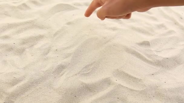 Рука малює напис сонце з променями на піску. Сонячне узбережжя моря і океану. Символ відпочинку та відпустки на курорті — стокове відео