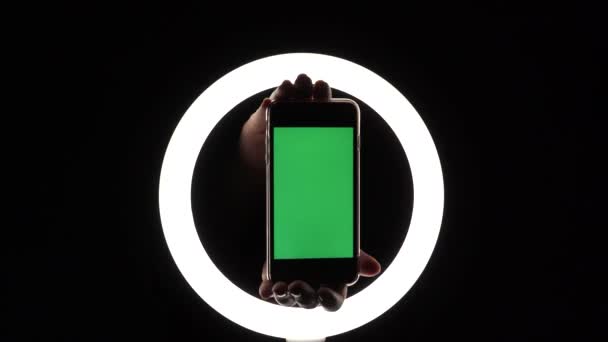 Le mani femminili mostrano il telefono primo piano su uno sfondo nero. mockup schermo verde per inserti pubblicitari — Video Stock