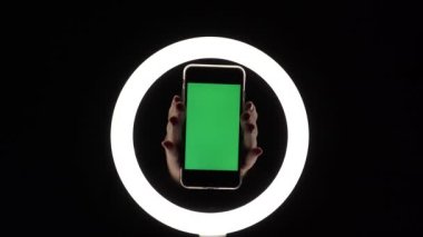 Kadın eli, telefonun siyah arka planda yakın çekimini gösteriyor. reklam eklemek için yeşil ekran modeli