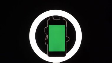 Kadın eli, telefonun siyah arka planda yakın çekimini gösteriyor. reklam eklemek için yeşil ekran modeli