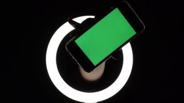 Kadın eli, telefonun siyah arka planda yakın çekimini gösteriyor. reklam eklemek için yeşil ekran modeli