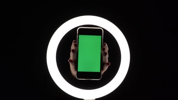 Mains féminines montrent le téléphone gros plan sur un fond noir. maquette d'écran vert pour insérer des annonces — Video