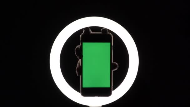 女性の手は黒の背景に電話のクローズアップを示しています。広告を挿入するための緑の画面のモックアップ — ストック動画