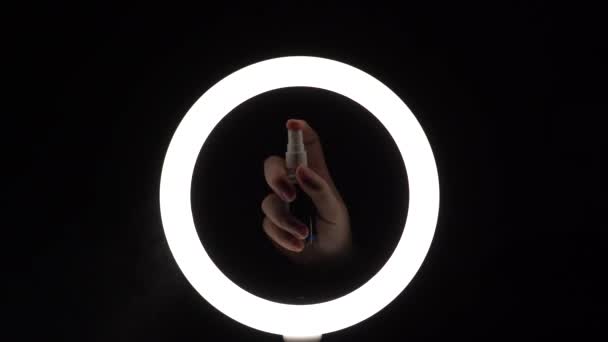 Verstuiver in vrouwelijke handen. sproeiwater. sprenkelende vloeibare close-up. waterstof op een zwarte achtergrond met verlichting van een ledlamp. verpulvering — Stockvideo