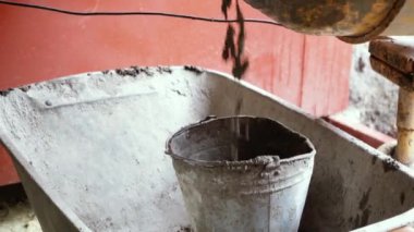 Beton karıştırıcı bina karışımını karıştırıyor ve bir kovaya döküyor. Dönüşümlü inşaat aleti yakın çekim. Gri yapım yapıştırıcılı inşaat işi