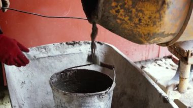 Beton karıştırıcı bina karışımını karıştırıyor ve bir kovaya döküyor. Dönüşümlü inşaat aleti yakın çekim. Gri yapım yapıştırıcılı inşaat işi