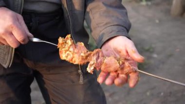 Sokakta mangal mangalında mangal yapan bir adam. Barbekü dışarıda. Doğada piknik. Şişte bir parça et yiyor.