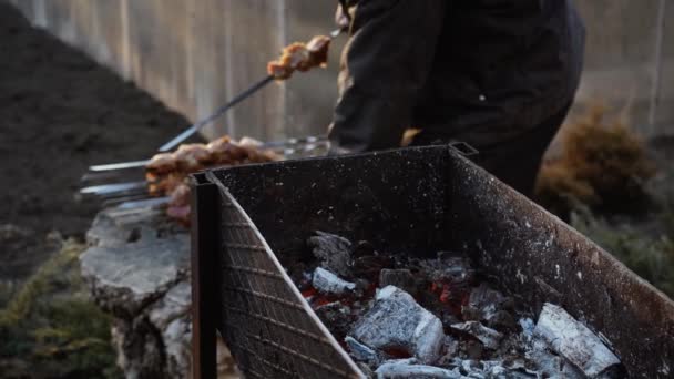 Mężczyzna gotuje grilla na szaszłykach na grillu węglem drzewnym na ulicy. Grill na świeżym powietrzu. Piknik w naturze. Przynęty kawałki mięsa na szpikulcu — Wideo stockowe