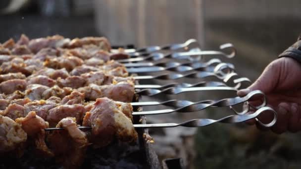 Een man kookt barbecue op spies op houtskool grill op straat. Barbecue buiten. Picknick in de natuur. Spins spiesen met gegrild vlees closeup — Stockvideo