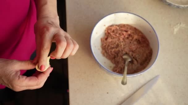 Egy nő gombócot készít a saját kezével tésztából és darált húsból egy közeli konyhában. Házi készítésű ételek főzése — Stock videók