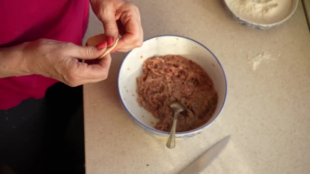 Uma mulher esculpe bolinhos com as próprias mãos a partir de massa e carne picada em uma cozinha em casa close-up. Cozinhar comida caseira — Vídeo de Stock