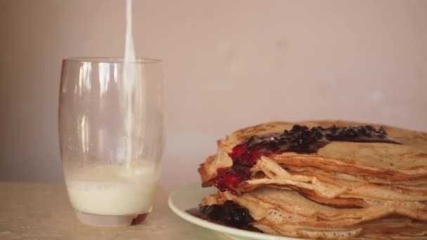 Selai close-up mengalir pada setumpuk pancake segar. Susu dituangkan ke cangkir. Makanan buatan sendiri di atas piring. kue-kue manis — Stok Video