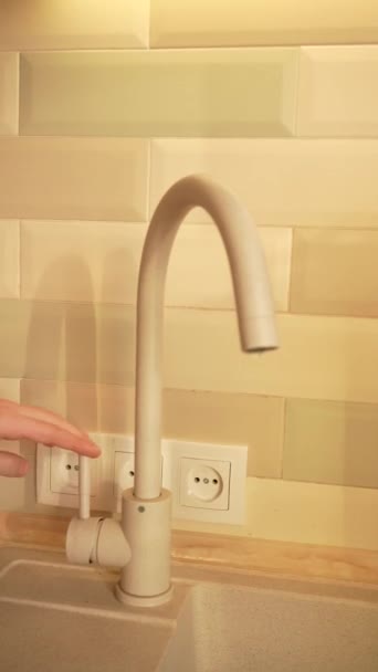 Une main de femme ouvre un robinet. L'eau se déverse d'un robinet dans un évier de cuisine et s'écoule dans un gros plan de vidange. Consommation d'eau potable propre. Travaux ménagers — Video