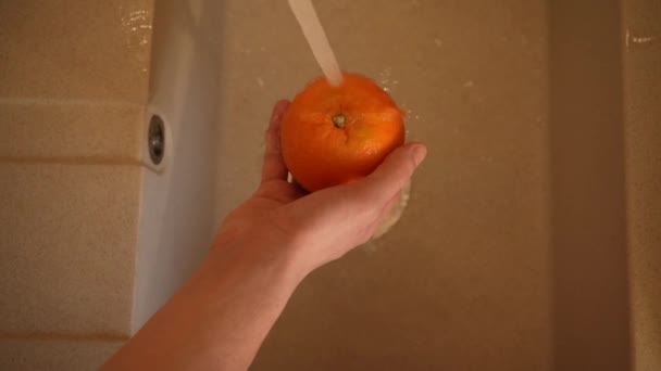 Mãos de uma governanta lava uma laranja na pia de cozinha close-up vista superior 4K. Nutrição adequada, cuidados de saúde — Vídeo de Stock
