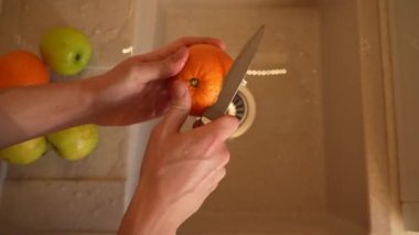 Bir temizlikçinin elleri mutfak lavabosundaki portakal kabuğunu temizler. Üst manzara 4K. Düzgün beslenme, sağlık hizmetleri