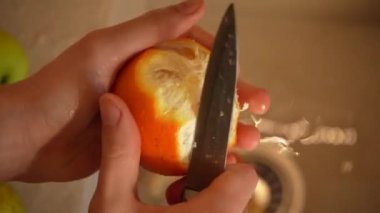 Bir temizlikçinin elleri mutfak lavabosundaki portakal kabuğunu temizler. Üst manzara 4K. Düzgün beslenme, sağlık hizmetleri