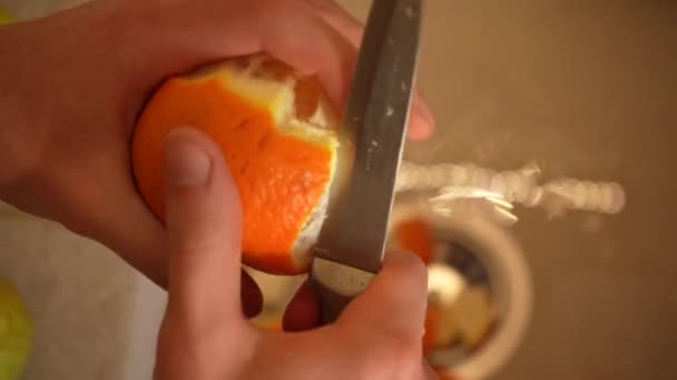 Τα χέρια μιας οικονόμου καθαρίζουν μια φλούδα πορτοκαλιού στο νεροχύτη της κουζίνας από κοντά. Σωστή διατροφή, υγειονομική περίθαλψη — Αρχείο Βίντεο