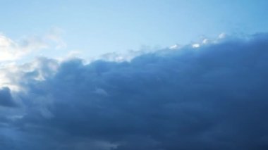 Gökyüzündeki gri bulutlar hızla hareket ediyor. Güneş ışınları bulutları delip geçer. Bulutlu hava.