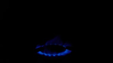Mutfak ocağındaki gaz ocağı yanıyor. Siyah arka planda, karanlıkta yanan mavi ateş alevi. Doğal gaz iltihabı. Doğal enerji taşıyıcısı, fosil yakıt.