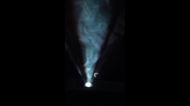 Spot ışıklarında yoğun duman parlıyor. Bir amatör film projektörü yoğun buhar kabarcıkları üzerinde parlar. Duman ve ışık konsepti.