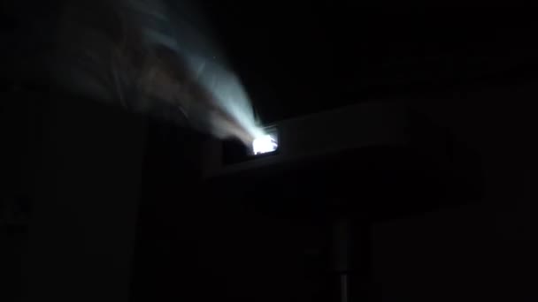 スポットライトの光の中で濃い煙が立ちます ホームムービープロジェクターは 蒸気の密なパフに輝きます 煙と光の概念 — ストック動画