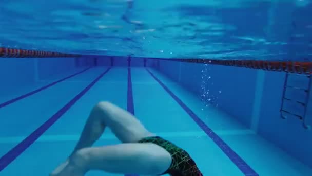 水着の同期水泳のスポーツ女性ダイビングのためのゴーグルで水泳のためのキャップでプールで訓練しています 水中での宙返りの体操や要素 — ストック動画