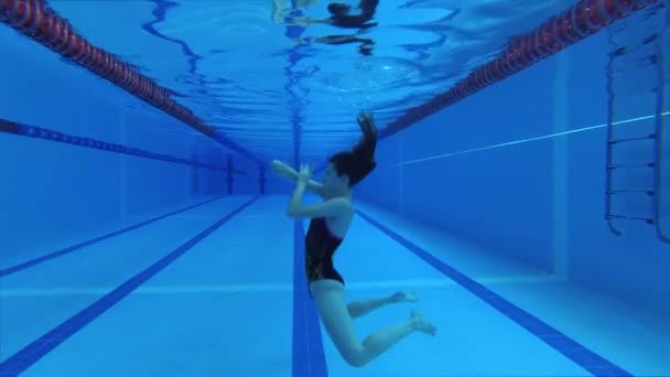 身穿运动服 戴着潜水镜 戴着泳帽的女运动员在游泳池里接受训练 体操和水中的元素 — 图库视频影像