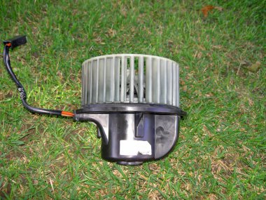 Elektrikli vantilatör arabadan çıkarılmış, çimlere, yan manzaraya, görüntüye yerleştirilmiş.