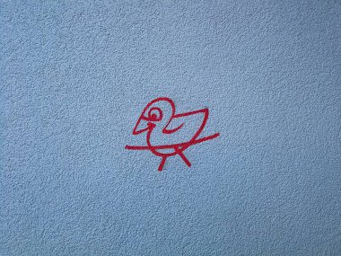 Mavi gök mavisi bir duvarda kırmızı boyalı bir kuş resmi.