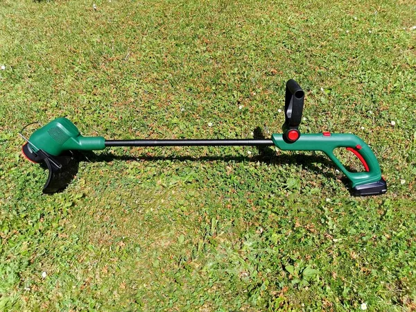 String electric lawnmower, trimmer, green plastic body, placed on the grass, image