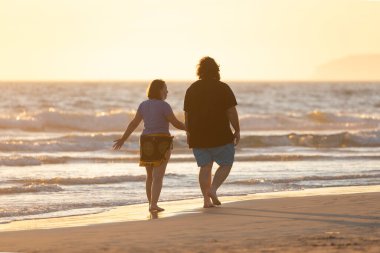 Zahara de los Atunes, İspanya - Eylül 03, 2021: Bir çift, gün batımında sohbet ederken sahilde yürüyüş yapıyor.