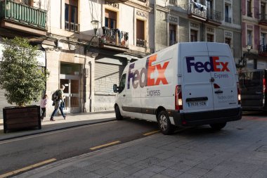 Bilbao, İspanya - 22 Aralık 2021: Bir FedEx Express paketi ve Bruno Mauricio Zabala Caddesi 'ne park etmek için eve servis minibüsü manevrası