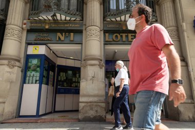 Zaragoza, İspanya - 12 Ağustos 2021: Bir numaralı eyalet piyango ve kumar idaresinin önünde, merkezde yer alan Coso Caddesi 'nde birkaç kişi yürüyor