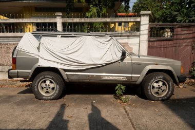 Bangkok, Tayland - 23 Ocak 2020: 1990 'lardan kalma eski bir Jeep Cherokee off-road arabası, Bangkok, Tayland' da lastikleri patlamış bir sokakta terk edilmiş.