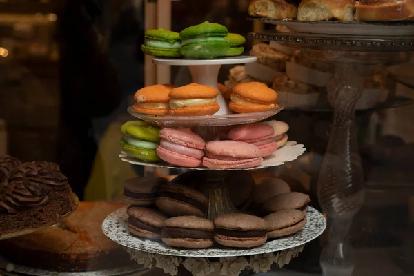 スペインのバルセロナにある菓子店の窓には クッキーサンドイッチのようなさまざまな色のマカロンの塔が展示されています — ストック写真