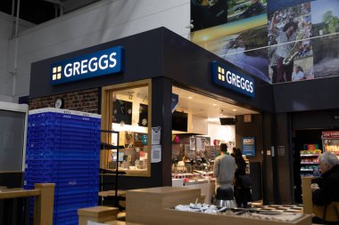 New Castle, İngiltere - 12 Aralık 2021: Bir Greggs mağazası, British Pastane zinciri, bazı müşterilerle birlikte, New Castle havaalanında, gece