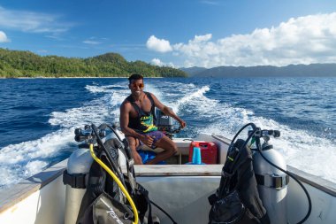 Raja Ampat, Endonezya - 05 Ekim 2019: Suyun kenarına bastırılmış verimli ve canlı bir orman arazisinde, bir adam teknesini Raja Ampat Adaları, Batı Papua, Endonezya 'da suya itiyor.