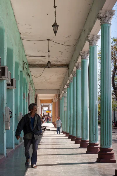 Cienfuegos, Küba - Nisan. 04, 2010: Şehrin şehir merkezi ve tarihi bölgesinde Paseo El Prado 'ya bakan sütunlu binaların atari salonlarında bir adam yürüyor