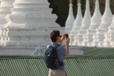 Mandalay, Burma - 3121 Aralık 2019: Batılı bir turist, Mandalay Tepesi yakınlarındaki Sanda Muni Pagoda 'da Budist stupalarının fotoğraflarını çekiyor.