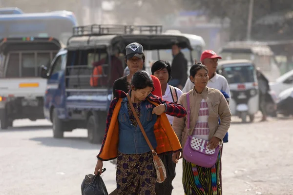 Mandalay, Burma - 3121 Aralık 2019: Bir kadın Mandalay 'daki Otoyol İstasyonu Chan Mya Shwe Pyi otobüs durağında bir grup yolcuyla yürürken cebinde bir şey arıyor
