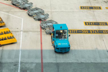Hanoi, Vietnam - Nov 06, 2019: Cargo tractors and cargo handler workers, maneuvering luggage trolleys at aircraft parking aprons, Terminal 2 of Noi Bai International Airport, Hanoi