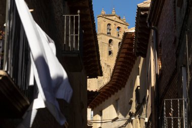 Çatıların saçakları, rüzgarda kuruyan beyaz bir çarşaf, ve arka planda San Salvador kilisesi, Luesia, Aragon, İspanya